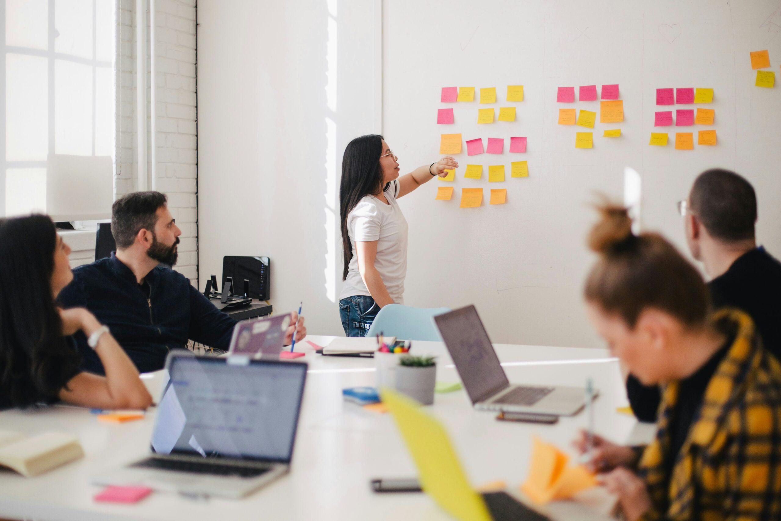 Woman adding sticky notes to a wall explaining corporate event planning ideas.