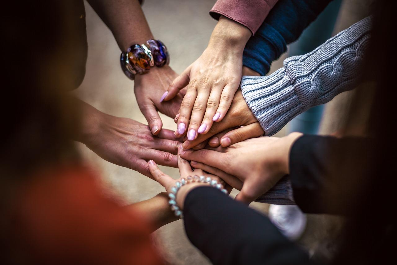 Group of people with hands together, symbolizing teamwork and unity 