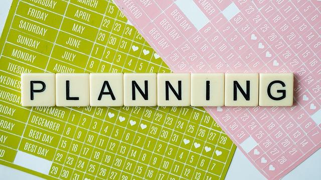 Planning spelled out with letter tiles on top of a calendar sheet. 