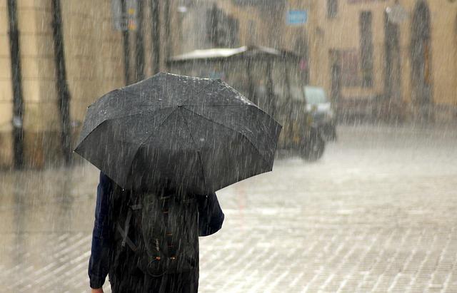 Man holding umbrella in heavy rain.